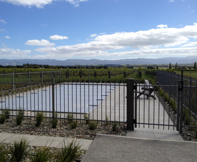Pool fencing regulations example with a metal pool fence and a self-closing gate around a covered pool