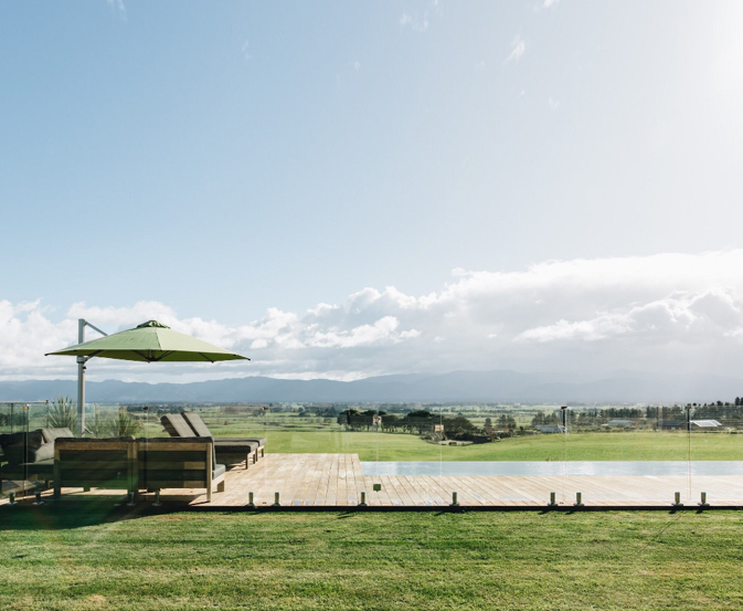 Glass swimming pool fencing beside a timber deck with open rural views