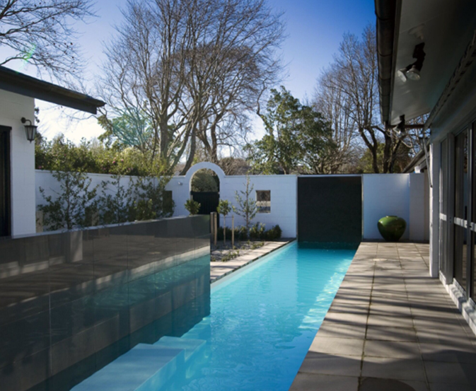 Glass swimming pool fencing along a narrow courtyard pool beside paving