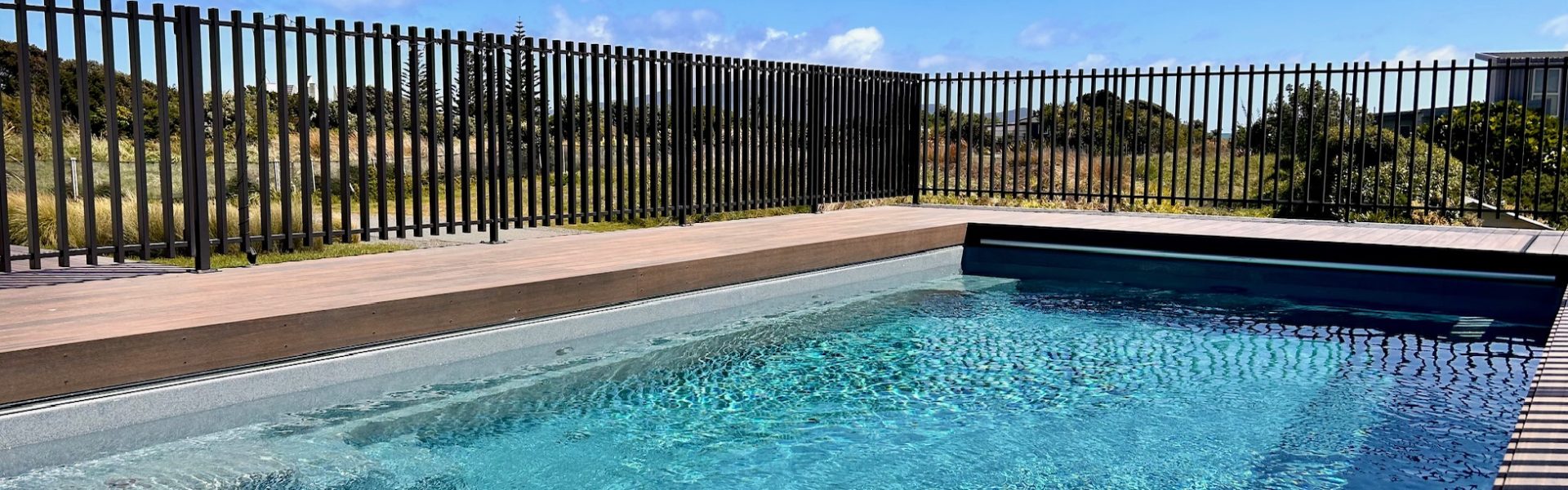 Modern swimming pool fencing requirements are shown with black metal fencing around a residential swimming pool
